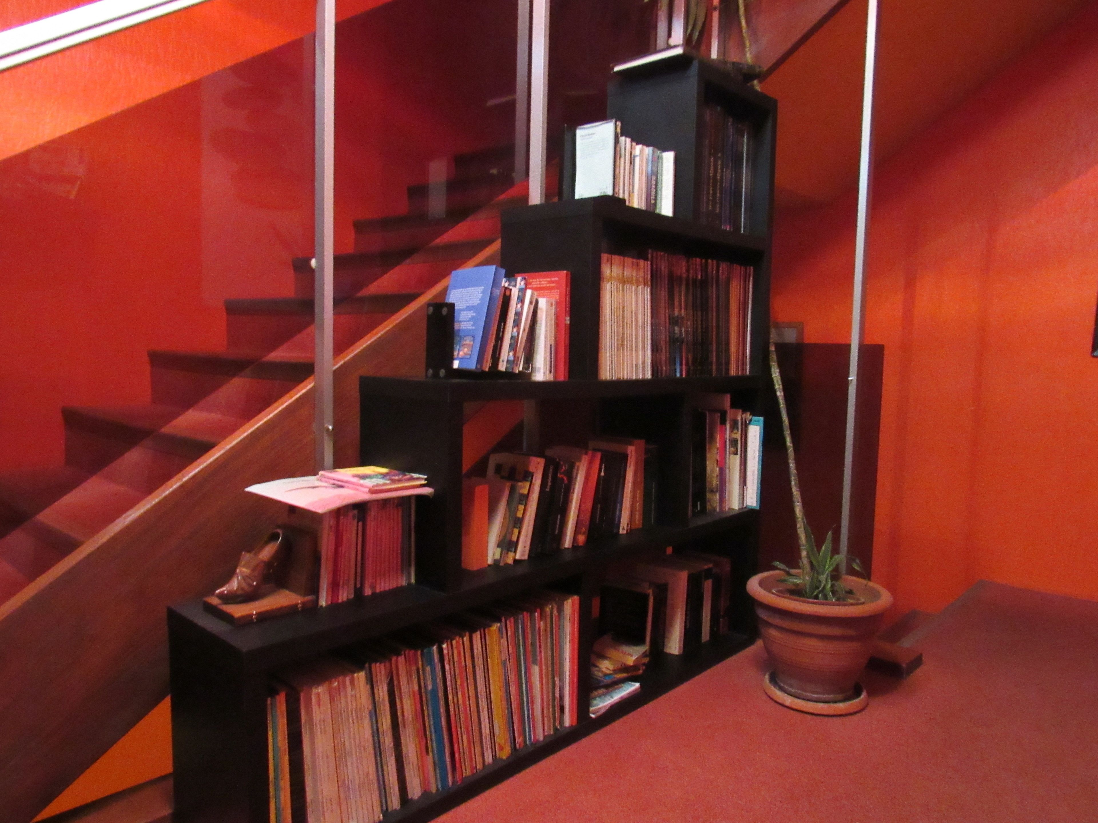 A staircase with a bookshelf filled with books and a potted plant.