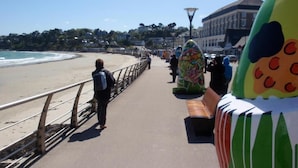 A coastal walkway with a metal railing, benches, and colorful sculptures. - Hôtel Les Sternes  (Louannec)