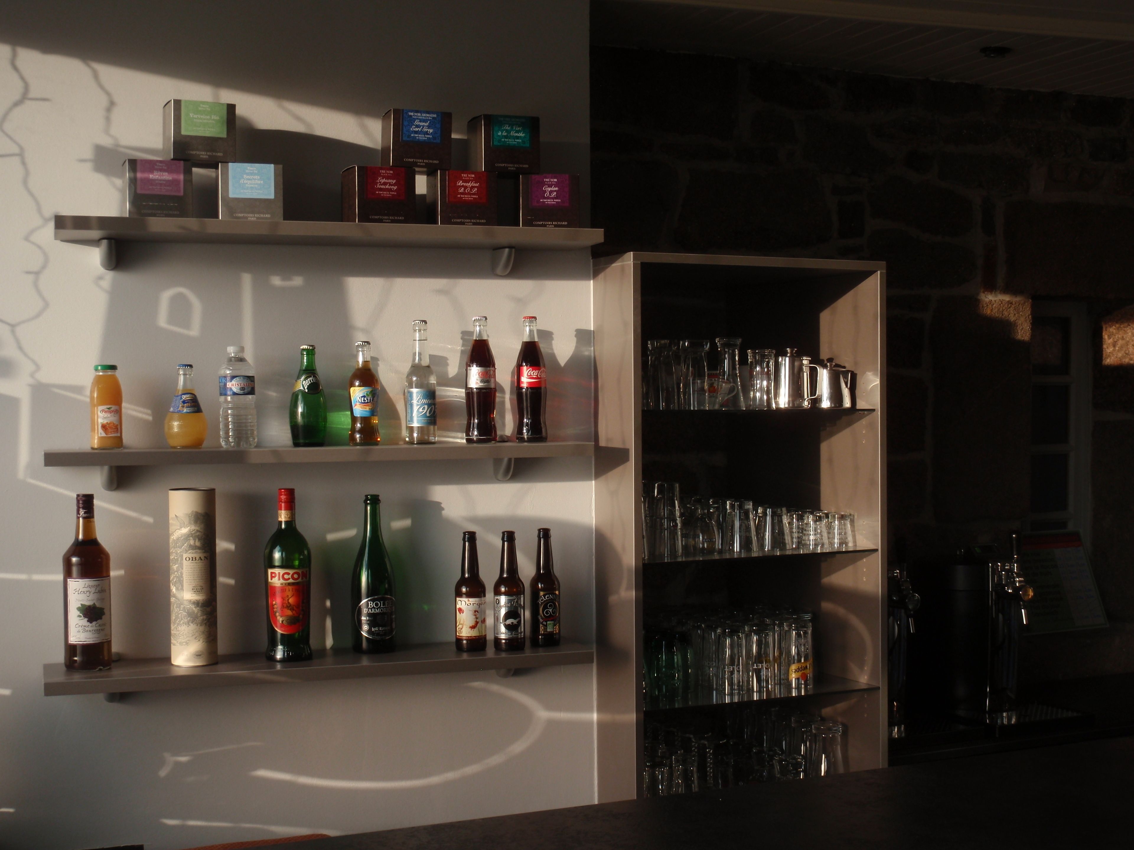 A bar area with shelves of bottles and glasses.