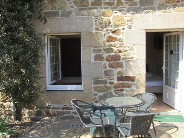 Un edificio de piedra con un patio que tiene sillas de mimbre y una mesa.