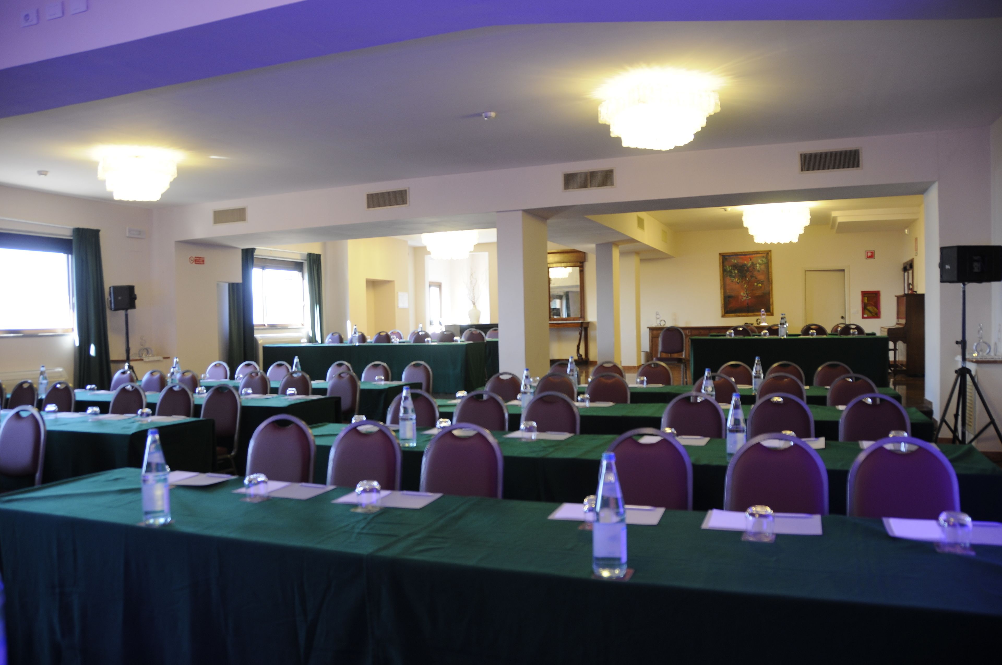 Une salle de conférence dotée de plusieurs tables et chaises, ainsi que de bouteilles d’eau et de plaques nominatives.