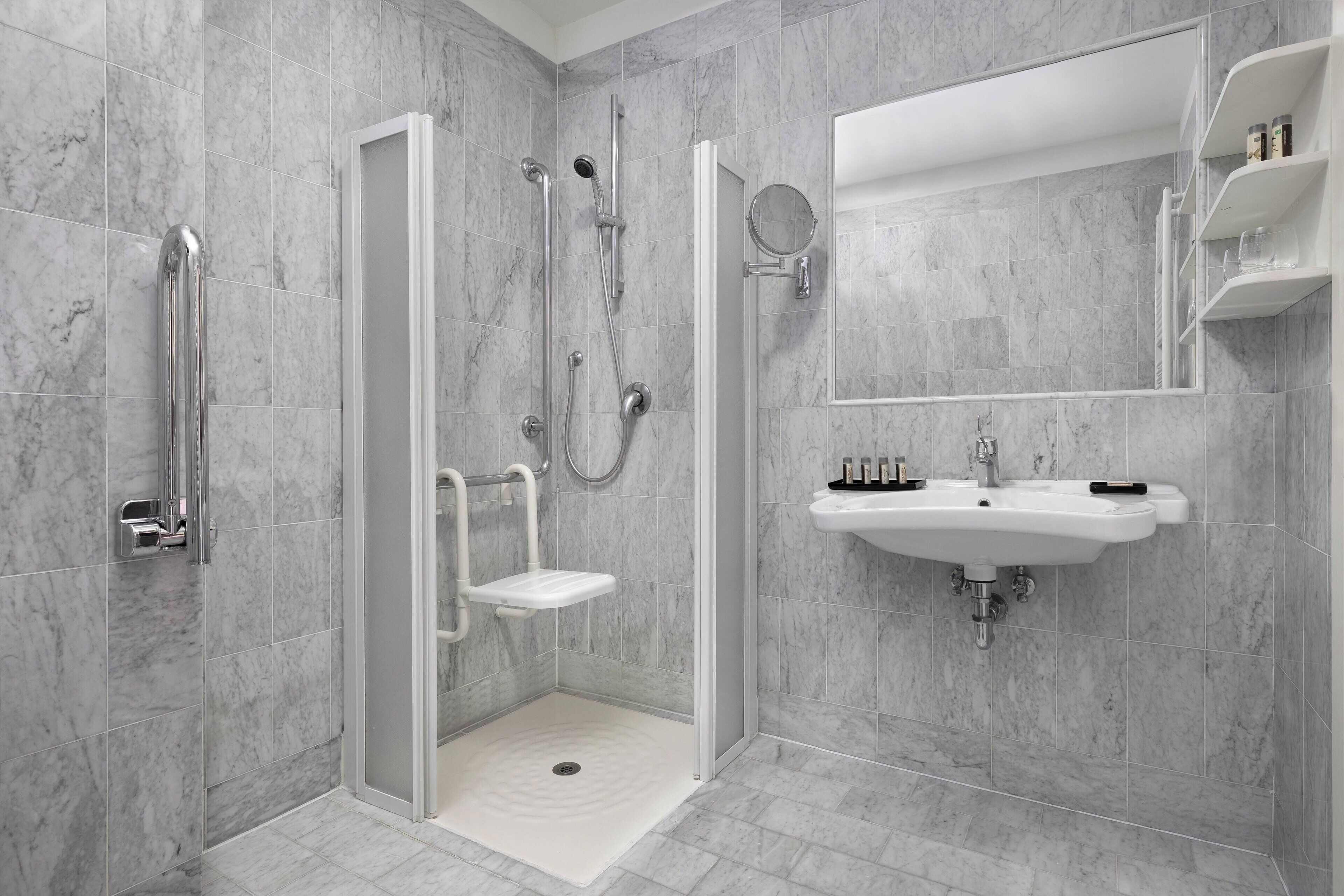 A modern bathroom with a walk-in shower, a sink, and a mirror.