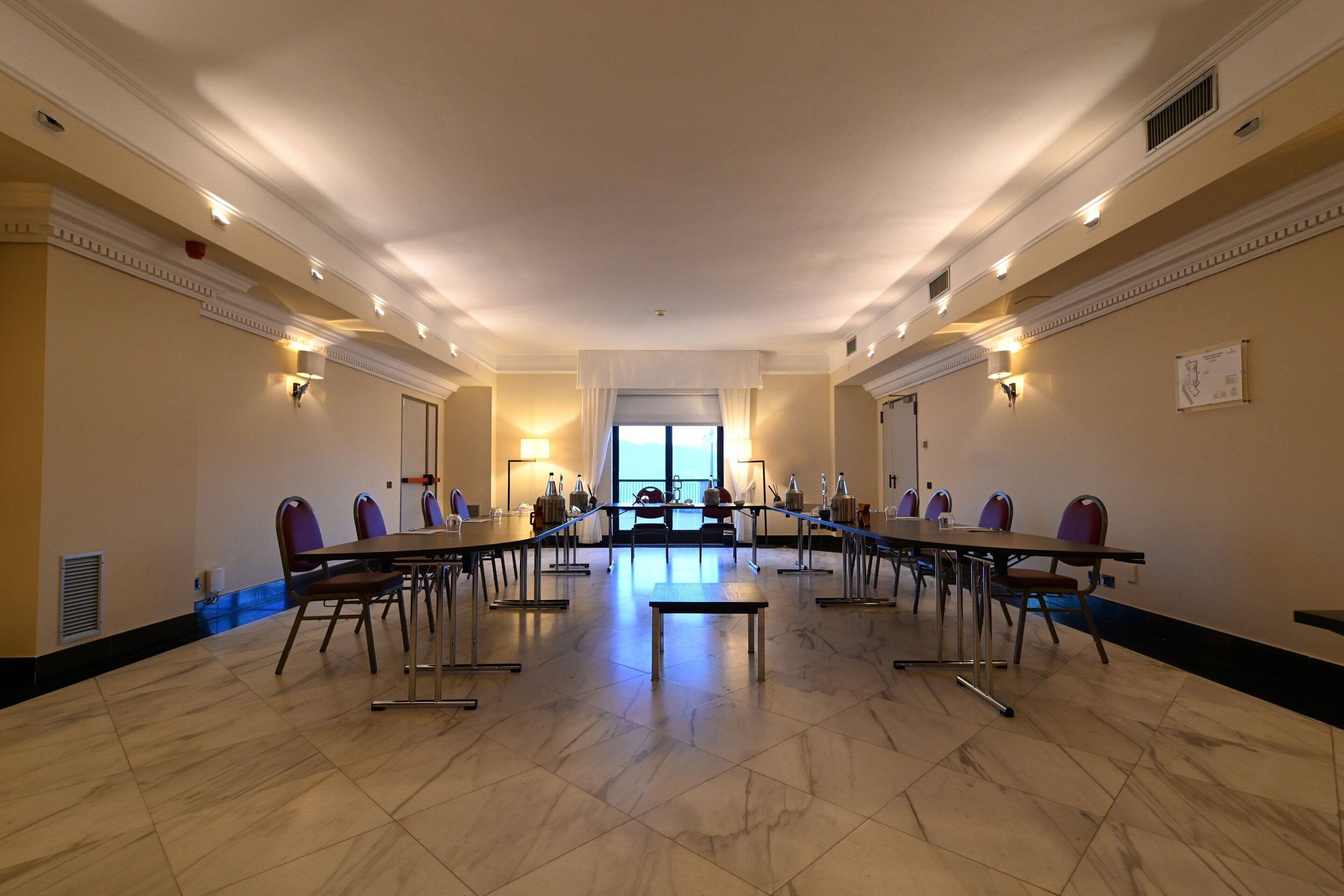 Una sala de conferències amb una taula llarga, cadires i una banca.