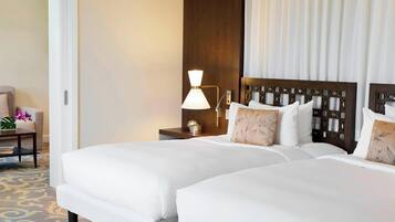 Een hotelkamer met twee bedden, een nachtkastje met een lamp, een stoel en een decoratief paneel aan de muur.