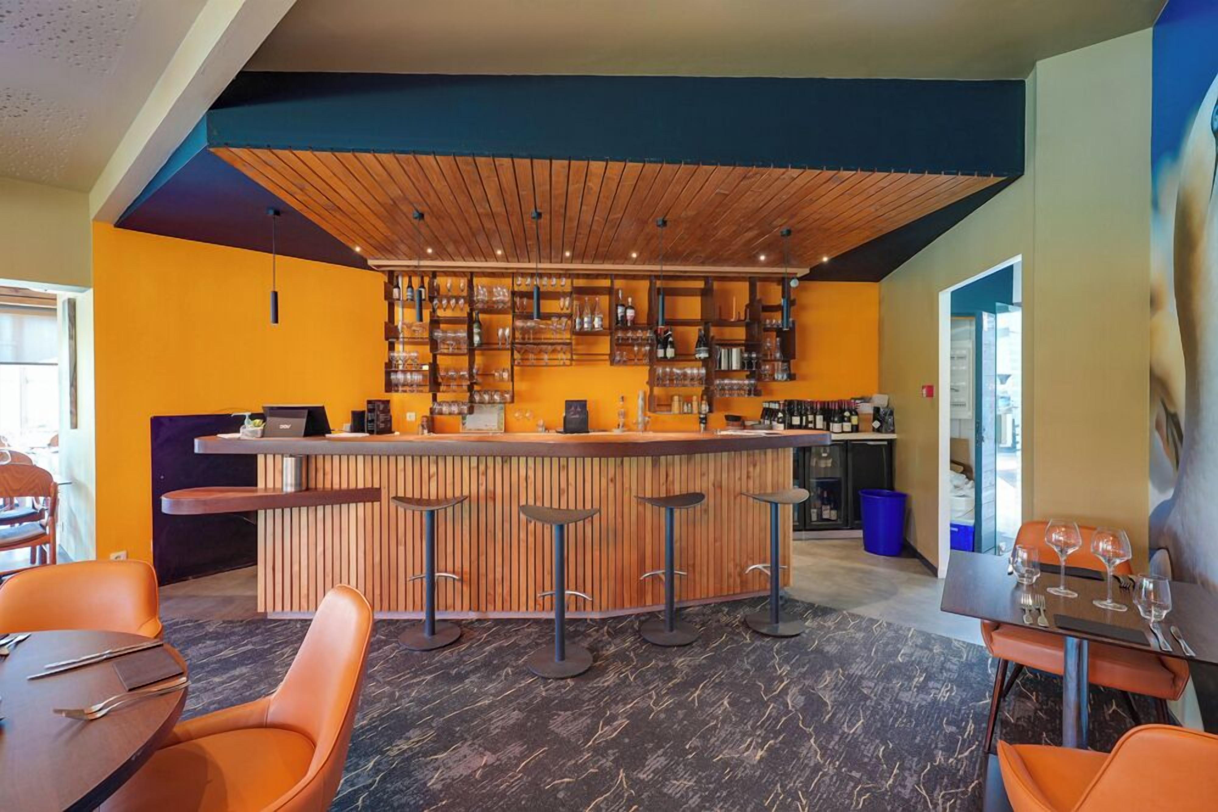 A bar area with a wooden ceiling, a counter with stools, and a seating area with tables and chairs.