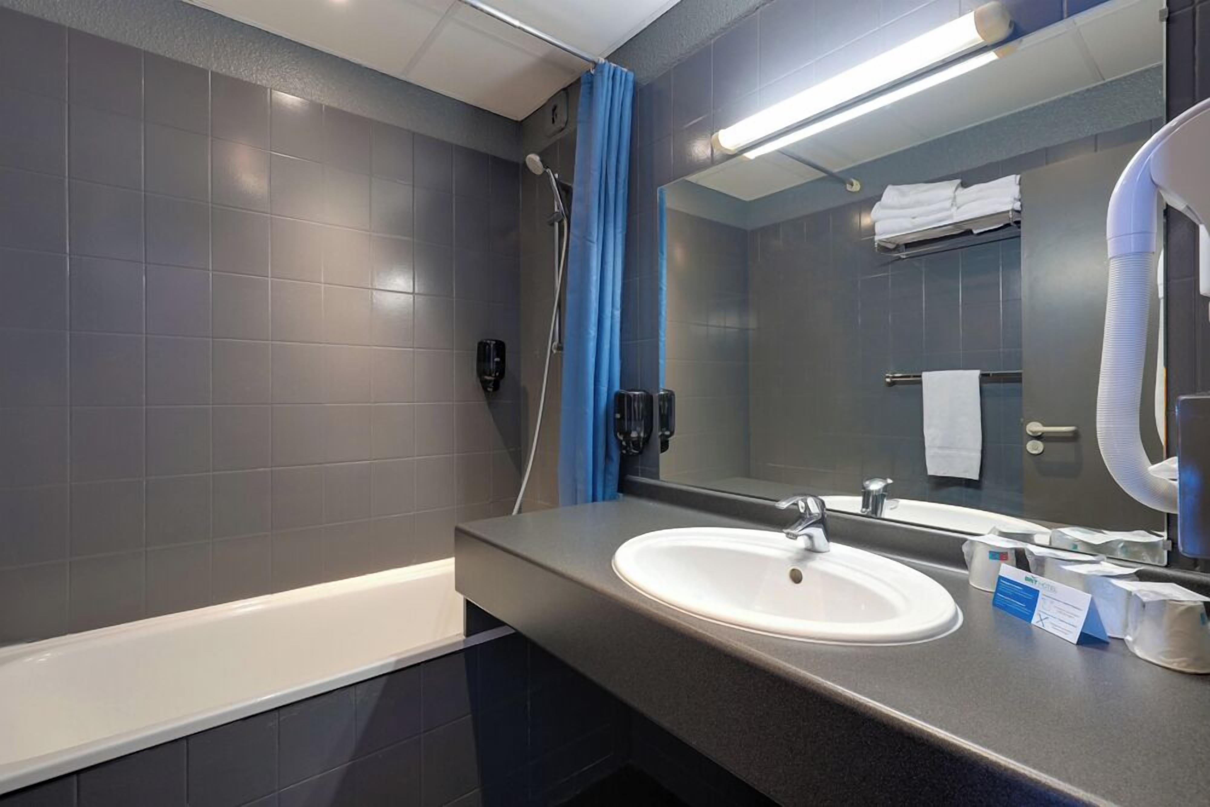 Un baño moderno con bañera, lavamanos, espejo y cortina de ducha.