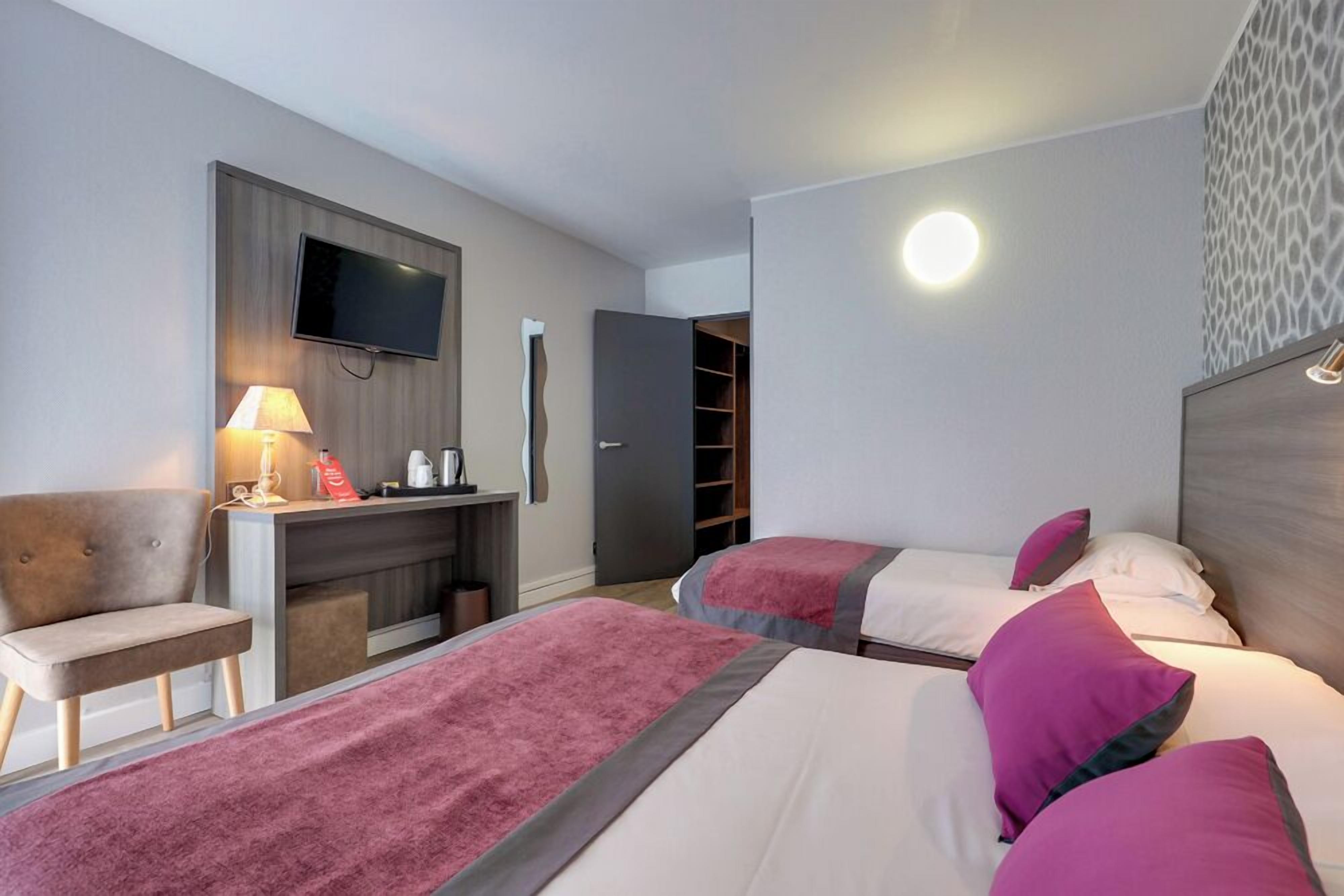 A hotel room with two beds, a desk, a TV, and a wardrobe.