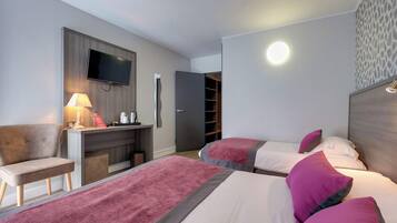 A hotel room with two beds, a desk, a TV, and a wardrobe.