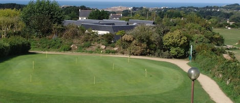 Campo de golf con vista despejada al océano y un edificio al fondo.