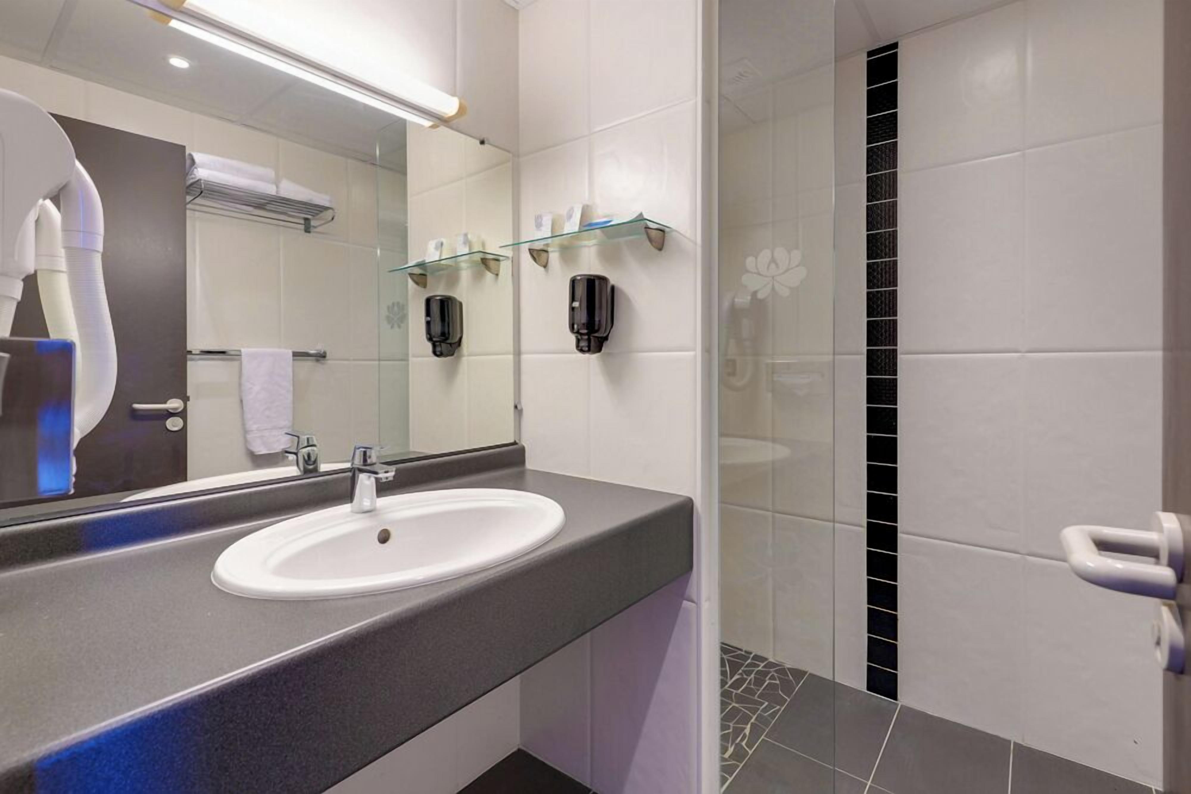 A modern bathroom with a sink, mirror, and glass shower enclosure.