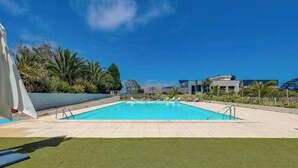 A rectangular swimming pool with a clear blue water surface, surrounded by a tiled deck and a grassy area. - Golf de St Samson (Pleumeur-Bodou)
