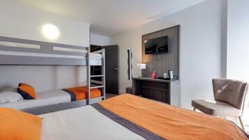 Ein Hotelzimmer mit Stockbetten, einem Schreibtisch, einem Flachbildfernseher, einem Sessel und einem Kamin.
