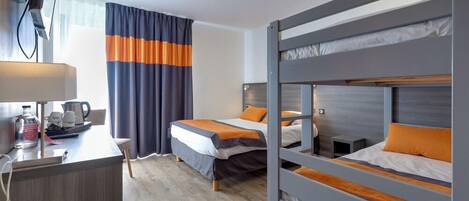 Habitación de hotel con dos camas, un escritorio con lámpara, televisor y ventana con cortinas.