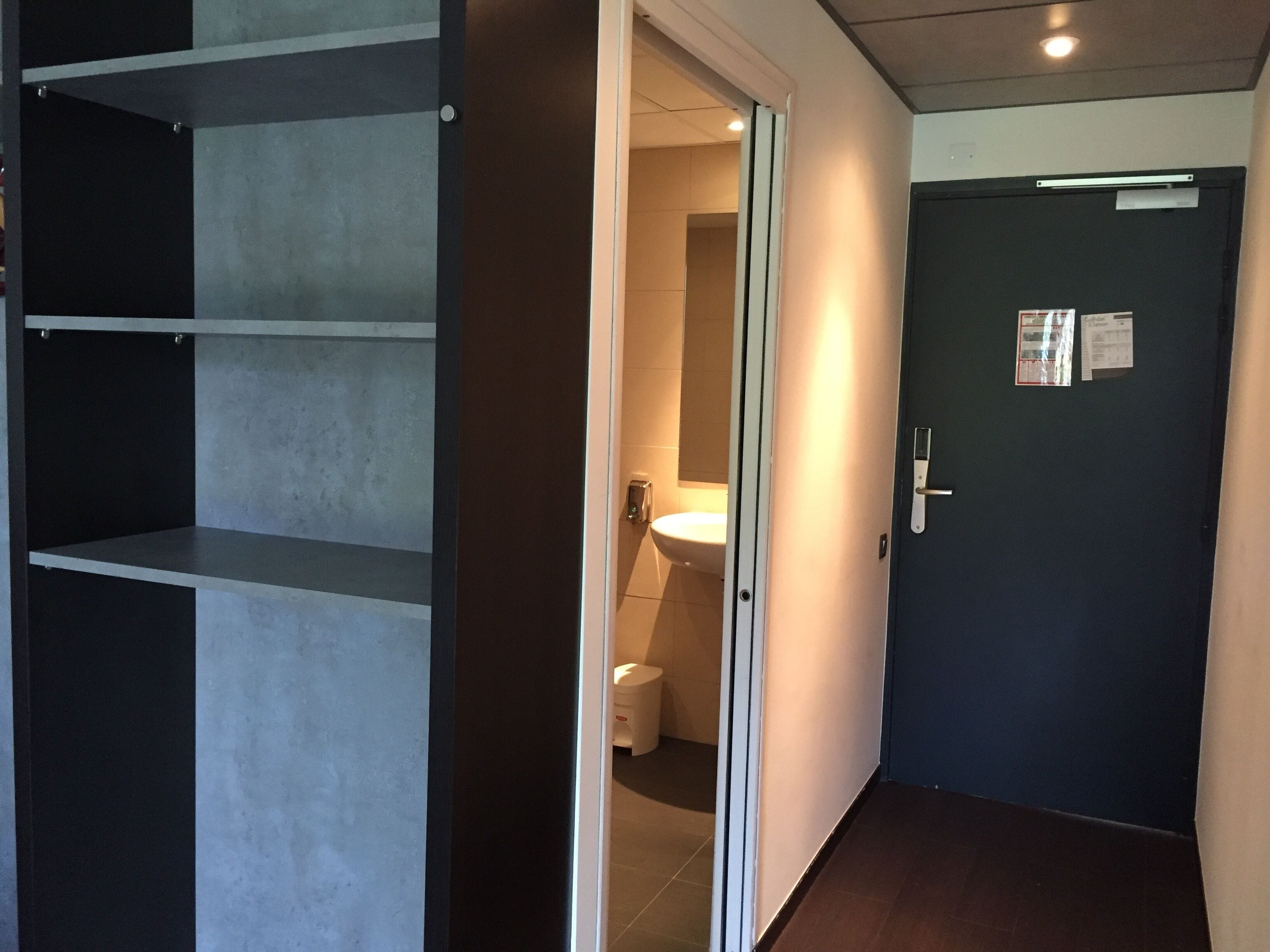 A hallway leading to a bathroom with a toilet and sink.