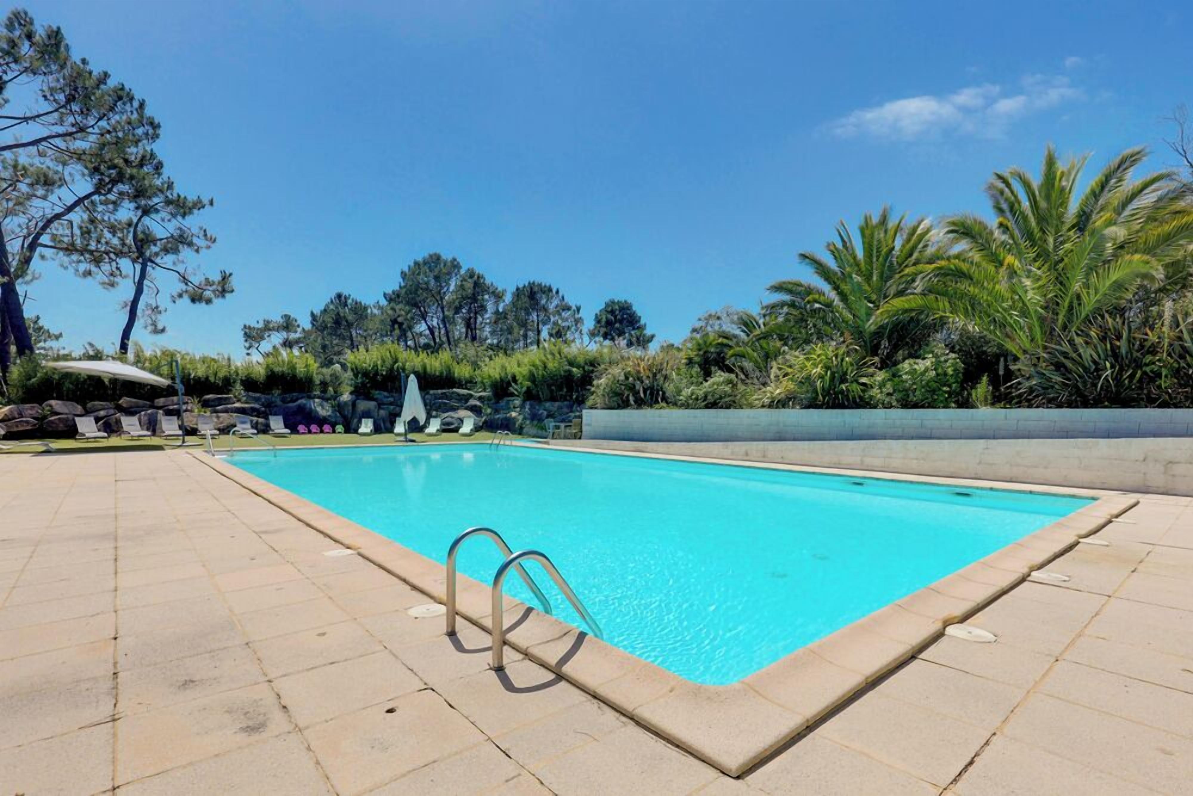 Une piscine rectangulaire à l’eau d’un bleu limpide, entourée d’une terrasse carrelée.