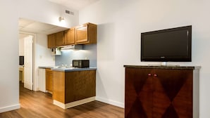 Una cocina moderna con armarios de madera, un microondas integrado y un televisor de pantalla plana montado sobre un mueble de madera oscura.