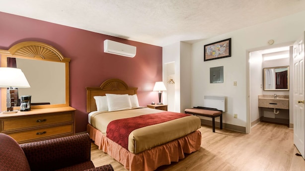Una habitación de hotel con cama, escritorio, silla, cómoda y baño.