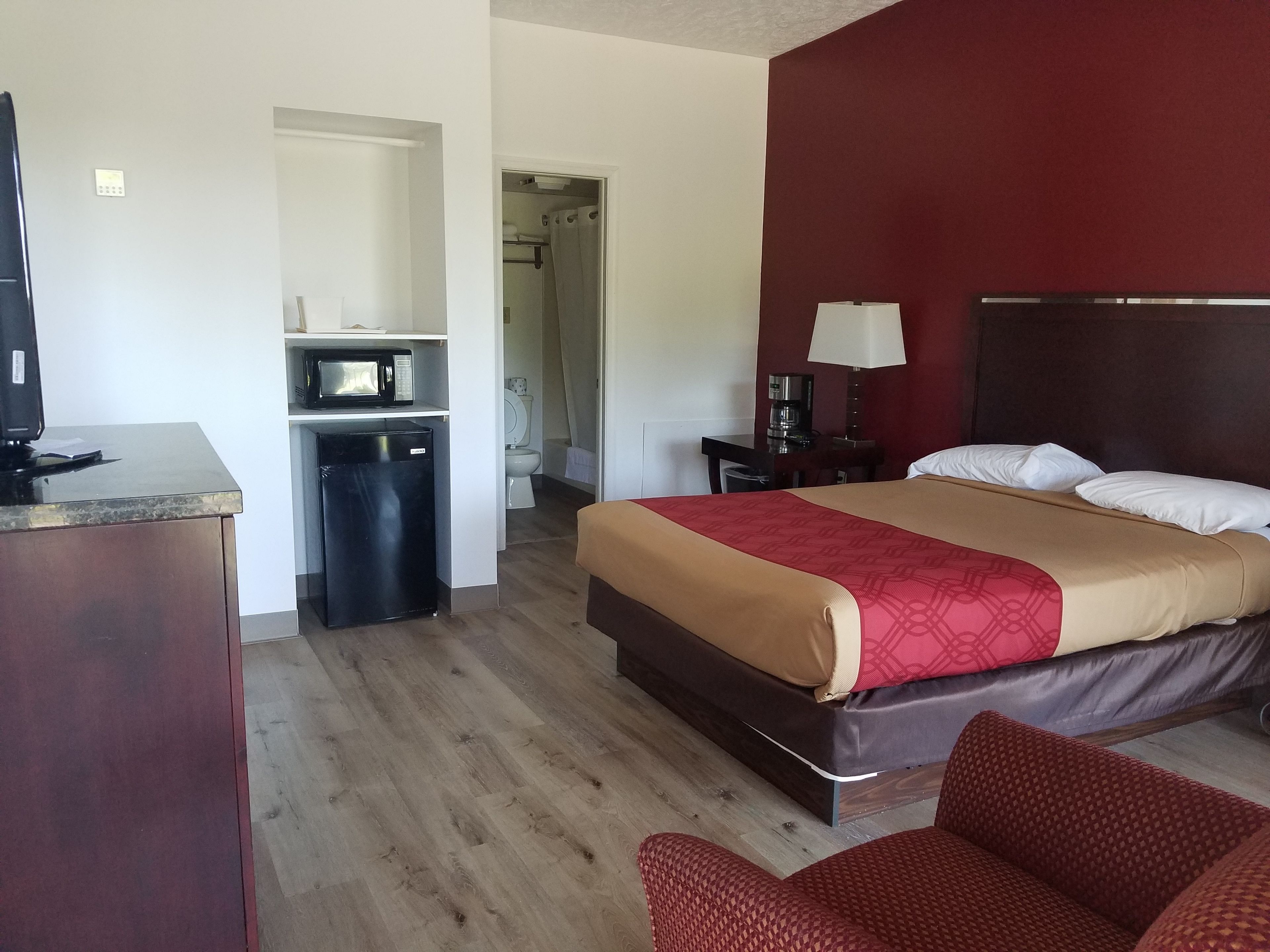 A hotel room with a bed, a desk with a computer, a microwave, and a small refrigerator.