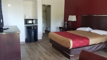 A hotel room with a bed, a desk with a computer, a microwave, and a small refrigerator.