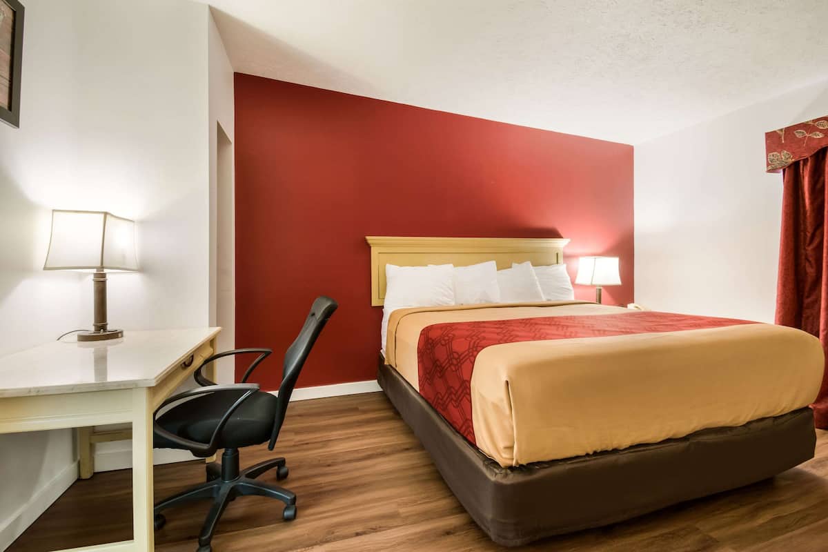 A hotel room with a bed, desk, and chair.