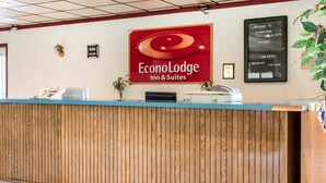 Mostrador de recepción en EconoLodge Inn & Suites con un letrero, un tablón de anuncios y una planta.
