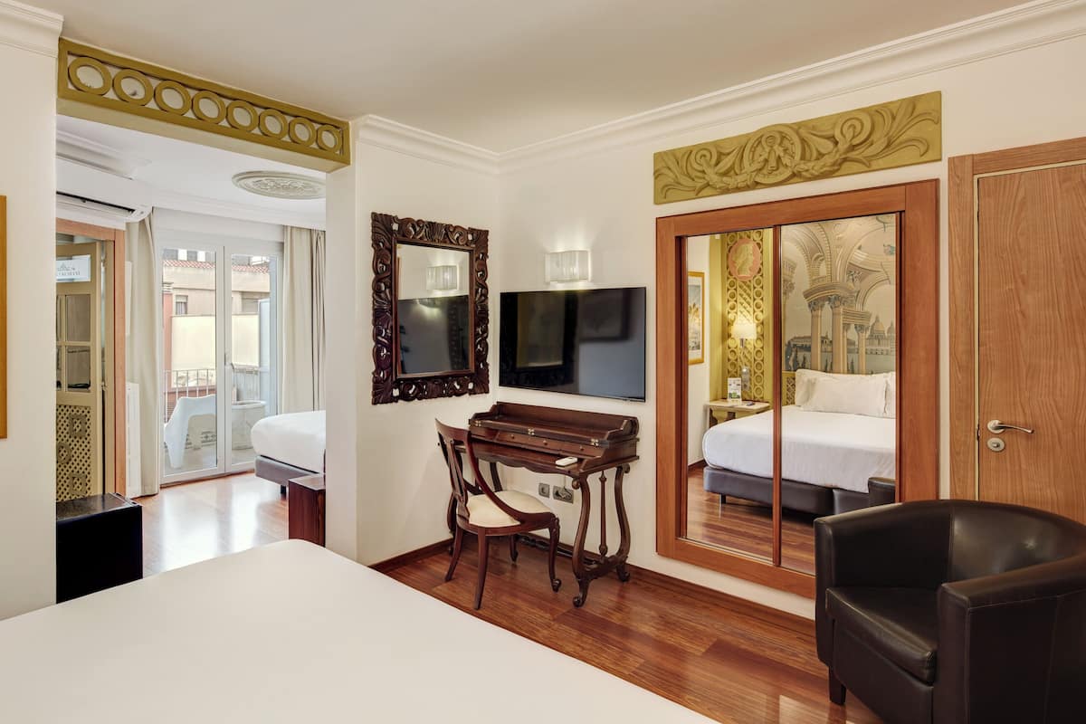 Ein Hotelzimmer mit Bett, Schreibtisch, Stuhl, Fernseher und einem großen Spiegel.