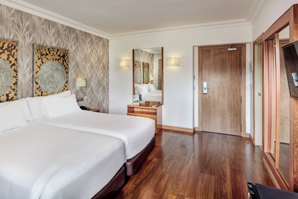 Ein Hotelzimmer mit einem großen Bett, einem Holzschrank, einem Fernseher und einem Spiegel.