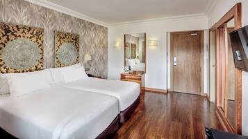 Een hotelkamer met een groot bed, een houten garderobe, een televisie en een spiegel.