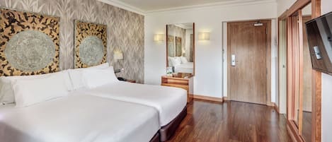 Una habitación de hotel con una cama grande, un armario de madera, un televisor y un espejo.