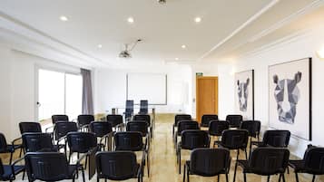 A conference room with rows of black chairs, a projector, and a whiteboard.