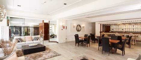 A spacious living area with a sofa set, a coffee table, and a dining area with chairs and a table.
