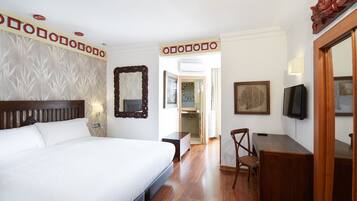 Una habitación de hotel con una cama grande, un escritorio, una silla, un televisor y un espejo.