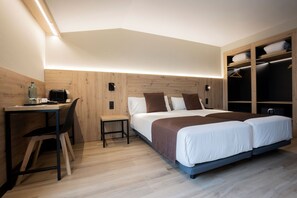 Una habitación de hotel moderna con un escritorio de madera, una cama con cabecera marrón y un vestidor con espacio para colgar.