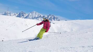 A person skiing on a snowy slope with mountains in the background.