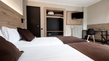 Una habitación de hotel con una cama, un armario, un escritorio y un televisor.