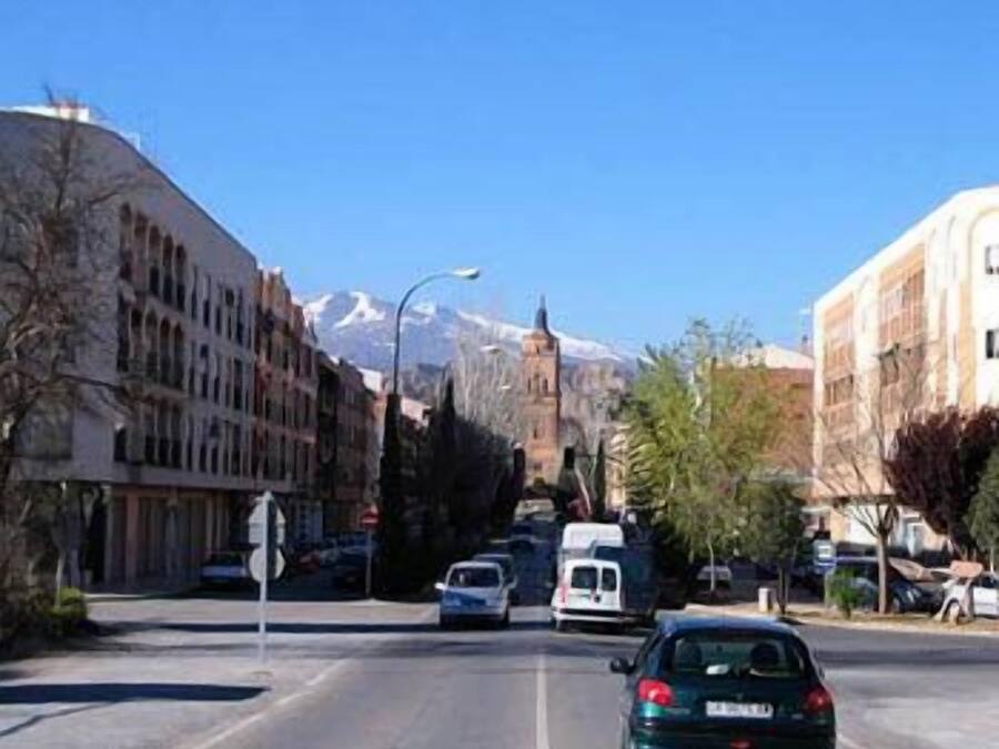 A street with buildings, a car, and a mountain in the background.