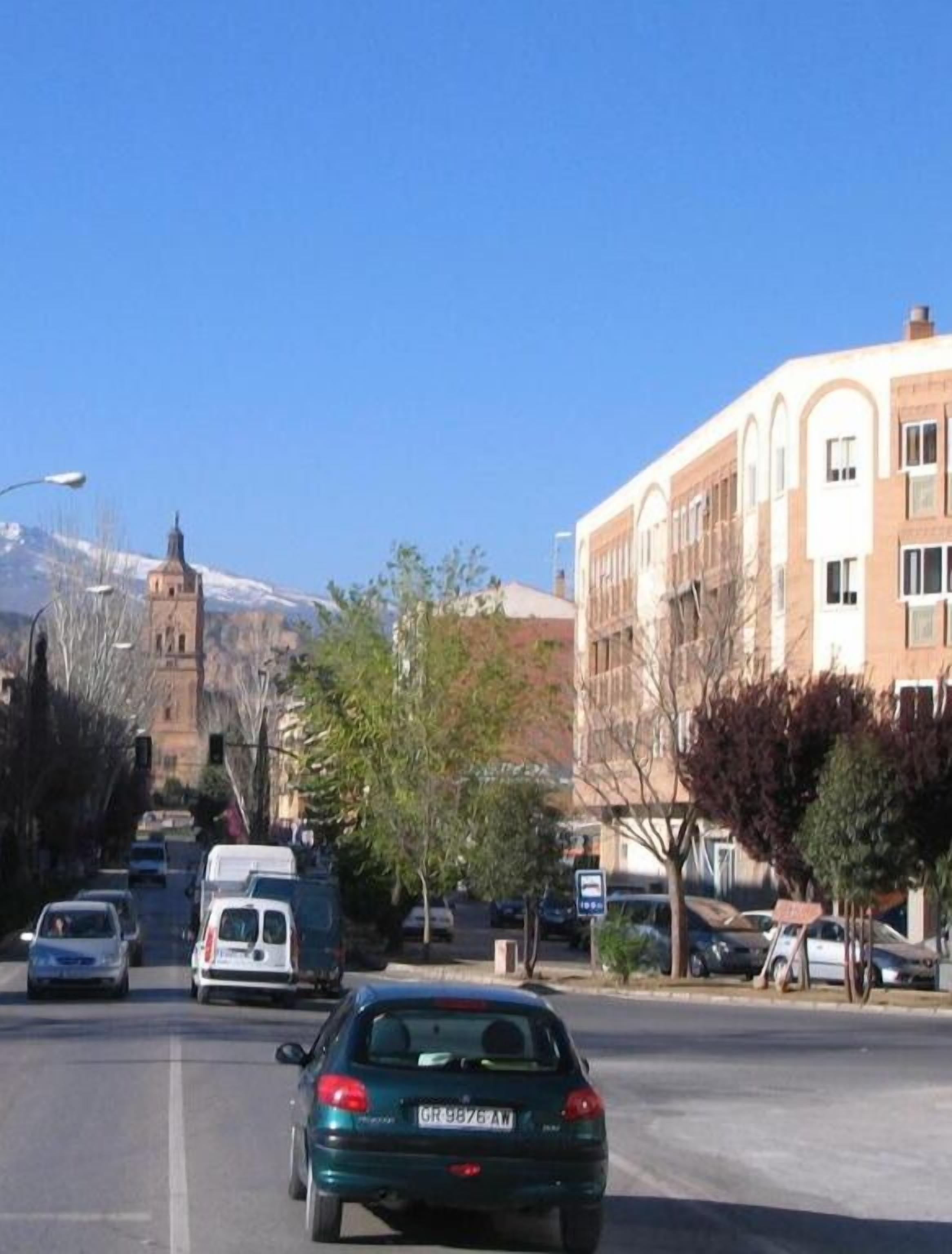 A street view with a building featuring arched windows and a mountain in the background.