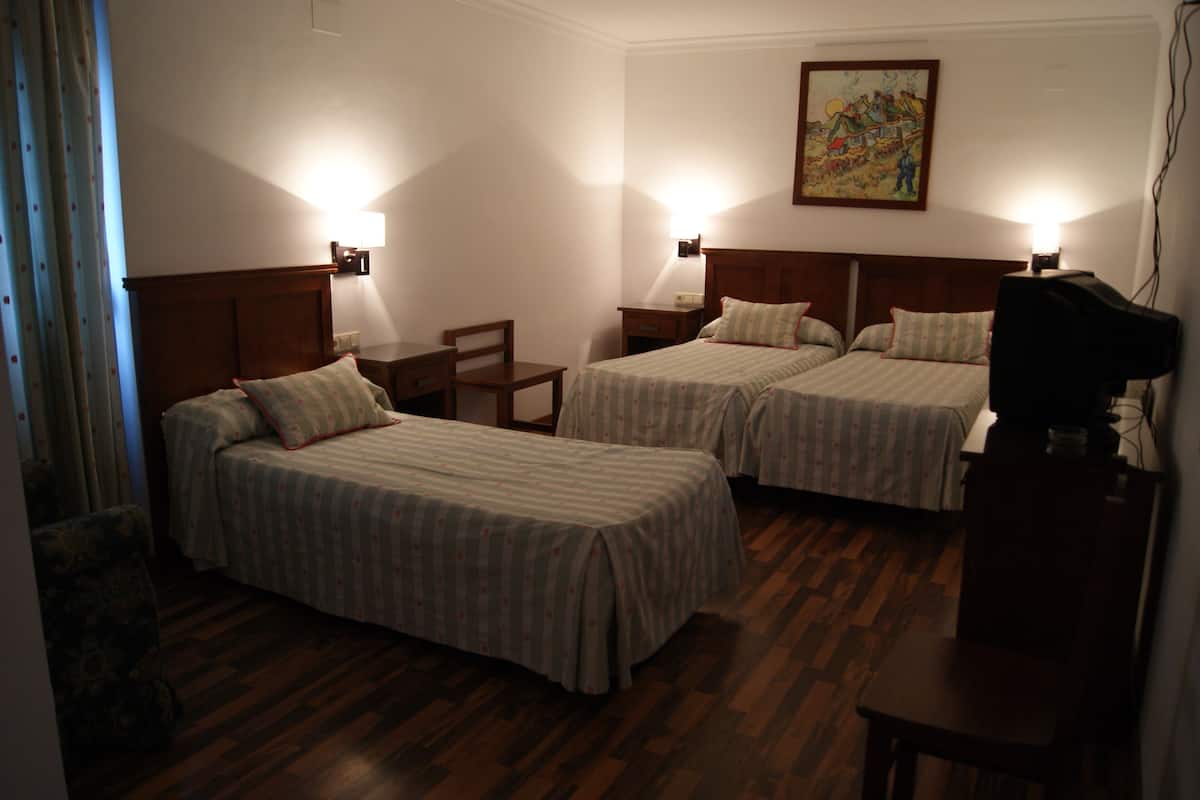 Ein Hotelzimmer mit zwei Betten, einem Schreibtisch, einem Sessel und einem Fernseher.