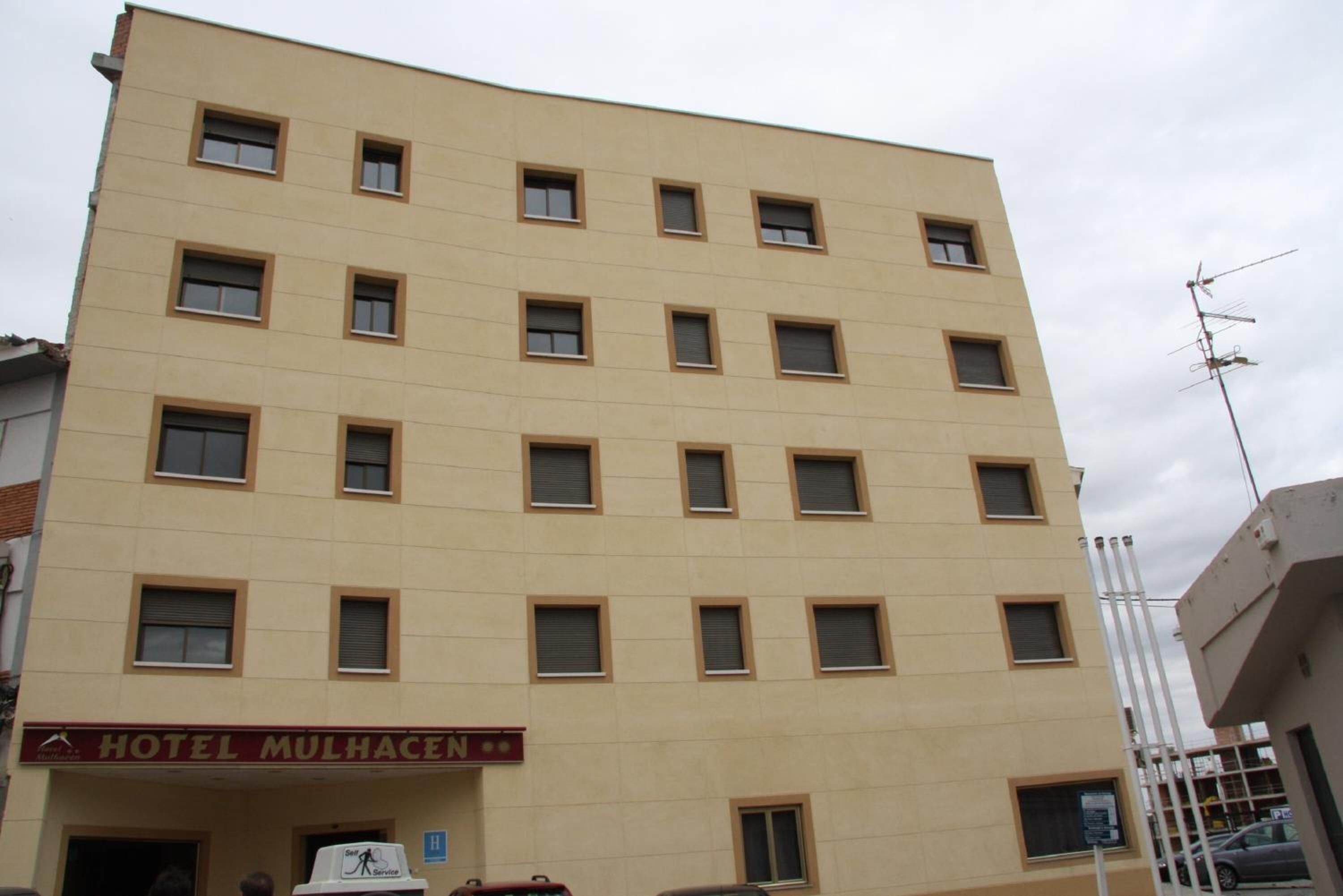 Un hotel de varios pisos con fachada plana, numerosas ventanas y un cartel que indica que es el Hotel Mulhacén.