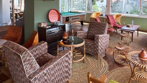 A cozy room with wicker furniture, a pool table, and a view of the outdoors. - Hotel Cadaques1962 (Cadaqués)