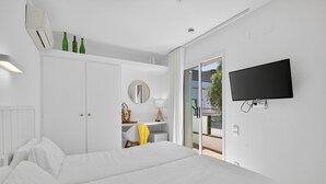 A bedroom with a bed, a desk, a chair, a mirror, and a TV. - Hotel Cadaques1962 (Cadaqués)