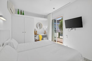 Un dormitorio con cama, escritorio, silla, espejo y televisor.