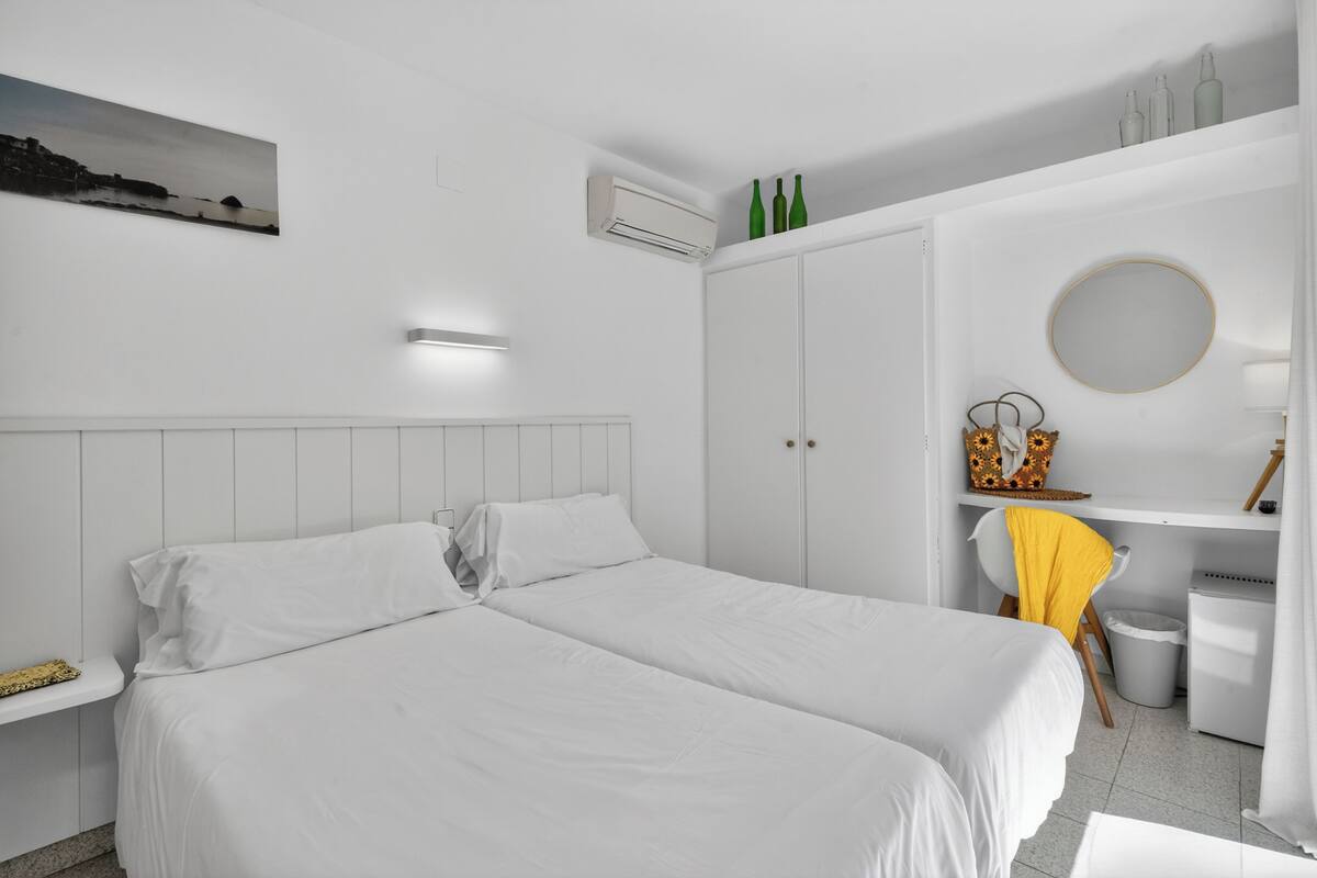 Moderni hotellihuone, jossa on suuri sänky, pieni työpöytä, tuoli, peili ja vaatekaappi.