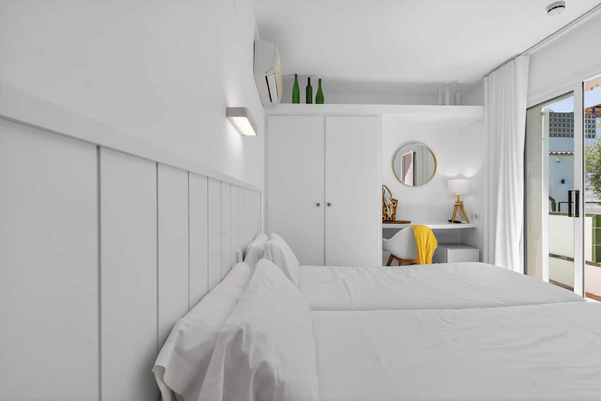 Moderni hotellihuone, jossa on suuri sänky, työpöytä tuolilla, peili ja näkymä ulos.