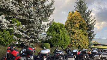 A row of motorcycles parked in a lot with trees and a cloudy sky in the background.