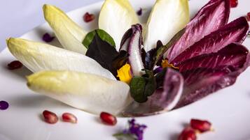 A white plate with a salad of mixed leaves and pomegranate seeds.