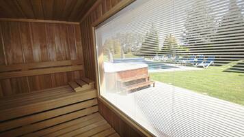 Una sauna con bancos de madera y un ventanal con persianas, con vistas a una piscina y un área de estar al aire libre.