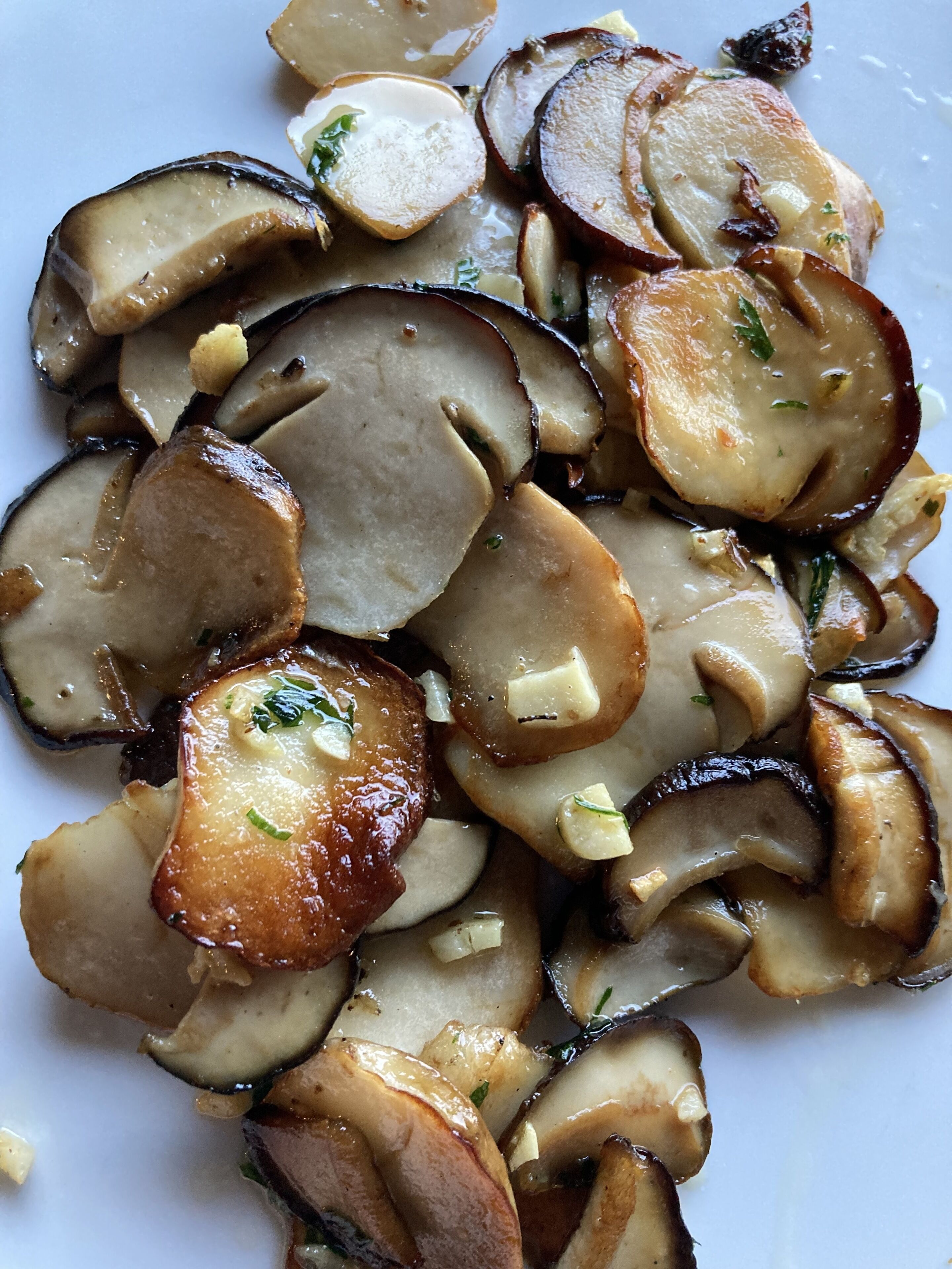 A close-up of sliced mushrooms with a creamy sauce and herbs.