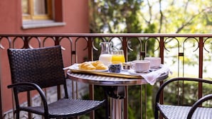 A breakfast setup with croissants, juice, and coffee on a balcony with wicker chairs and a metal table. - Hotel del Prado (Puigcerda)