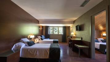 A hotel room with two beds, a desk, a chair, and a television.